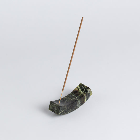 Smooth, handcrafted serpentine stone curved incense holder on a white background.