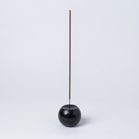 Full view of the solid black onyx sphere incense holder, showcasing its heavy mineral materiality on a white background.