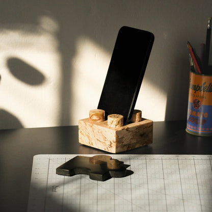 Close-up of the creamy soapstone phone stand in use, highlighting its Andean materiality and warm tones.
