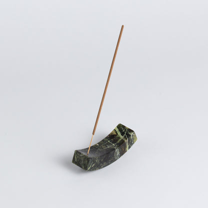 Smooth, handcrafted serpentine stone curved incense holder on a white background.