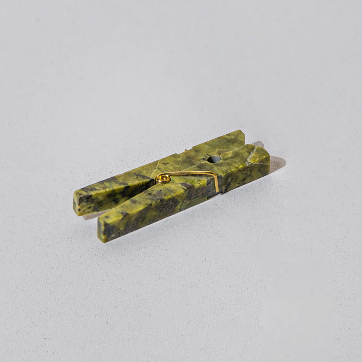 Serpentine green gemstone laundry clip highlighting natural Andean stone veins on a white background.
