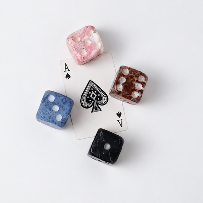 Side angle of the set of 4 natural stone dice showcasing their volume on a white background.