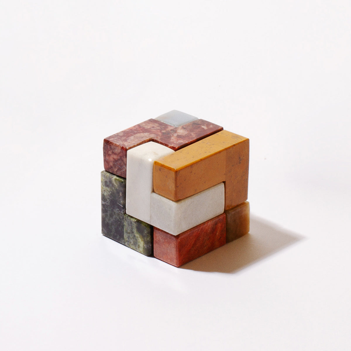 Close-up view of the natural Andean stone cube, highlighting the rich mineral veins and smooth carved finish against a seamless white backdrop.