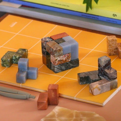Disassembled gemstone puzzle pieces resting organically in a quiet luxury setting.