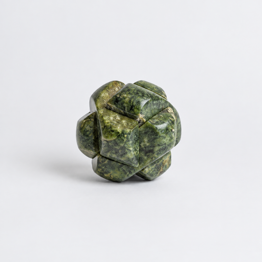 A spherical Kongming burr puzzle carved from mottled green nephrite jade against a plain white background.