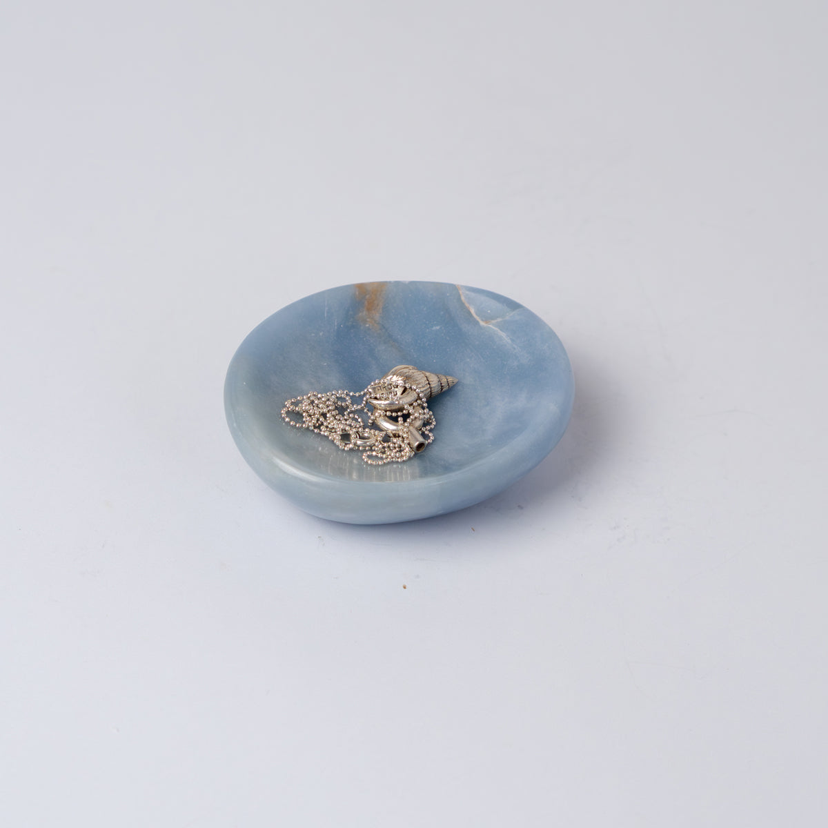 Organic 4-inch blue angelite gemstone catch-all dish displaying soft natural hues on a white background.
