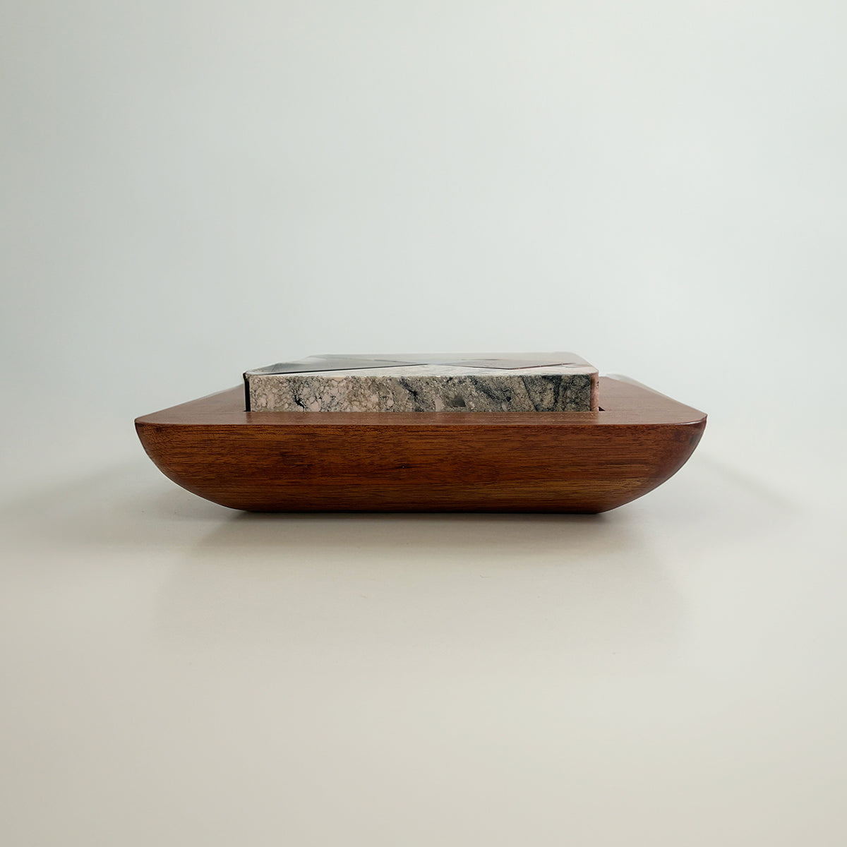 Side view of the wooden base holding the puzzle. The image shows the thickness of the carved stone pieces against a white background.