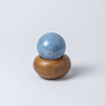 Solid blue angelite stone handle resting on top of the round wooden container, fitting perfectly to function as a lid, against a white background.