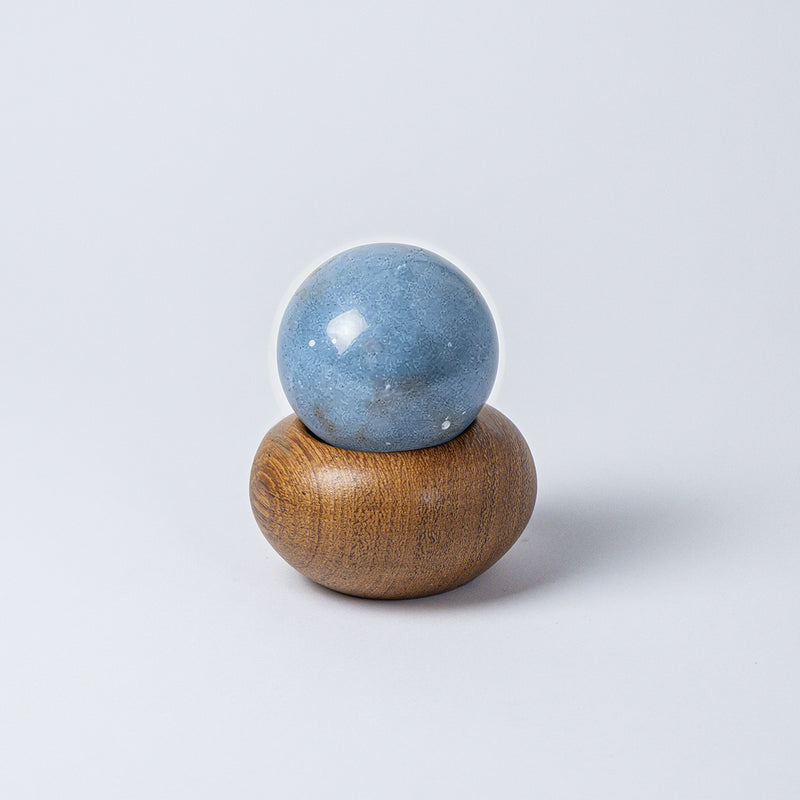 Solid blue angelite stone handle resting on top of the round wooden container, fitting perfectly to function as a lid, against a white background.