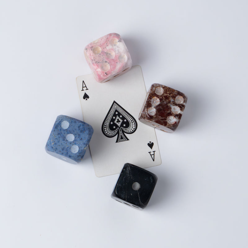 Side angle of the set of 4 natural stone dice showcasing their volume on a white background.